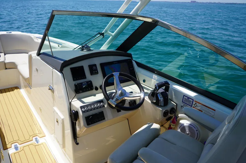 Slide: The Image of 2019 Boston Whaler 270 Vantage boat cockpit with steering wheel and controls on open water. - 11