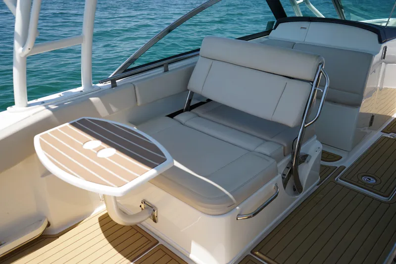 Slide: The Image of 2019 Boston Whaler 270 Vantage boat interior with cushioned seating and wooden table. - 17