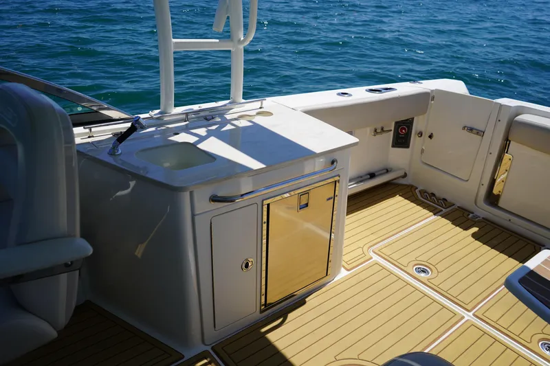 Slide: The Image of 2019 Boston Whaler 270 Vantage boat interior with sink and storage, on open water. - 18