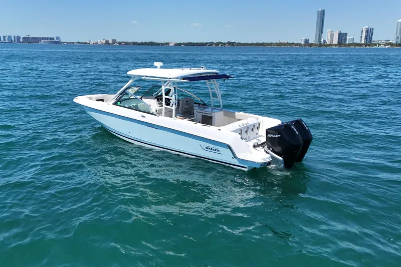 Slide: The Image of 2019 Boston Whaler 270 Vantage boat cruising on clear blue water near city skyline. - 2