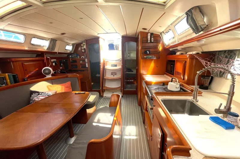Slide: The Image of Interior of a 2007 Beneteau 423 yacht, featuring a cozy dining and kitchen area. - 30
