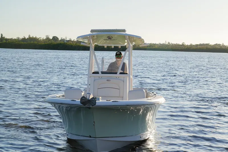 Slide: The Image of 2022 Sea Hunt Ultra 229 boat cruising on a calm lake under clear skies. - 15