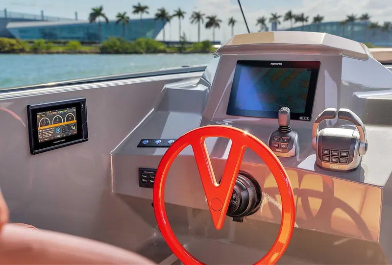 Slide: The Image of 2021 Vanquish Yachts VQ 45 helm with modern controls and vibrant red steering wheel. - 23