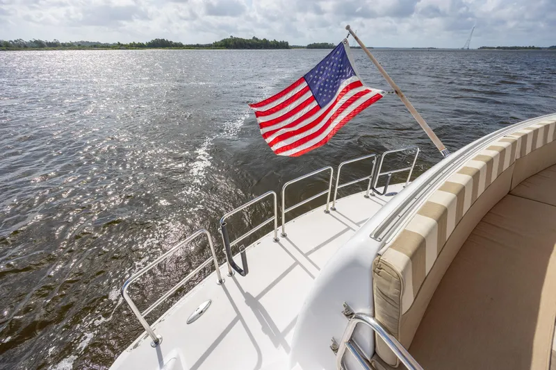 Slide: The Image of 2008 Hatteras 64 Motor Yacht with American flag on open water. - 100