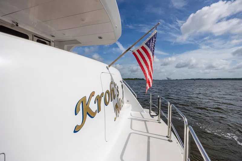 Slide: The Image of 2008 Hatteras 64 Motor Yacht with American flag on deck, cruising on open water. - 101