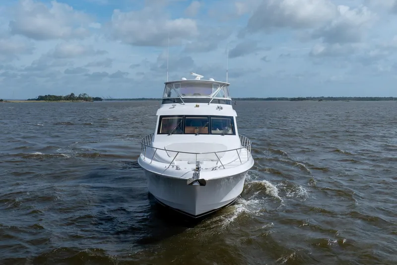 Slide: The Image of 2008 Hatteras 64 Motor Yacht cruising on open water under a cloudy sky. - 11