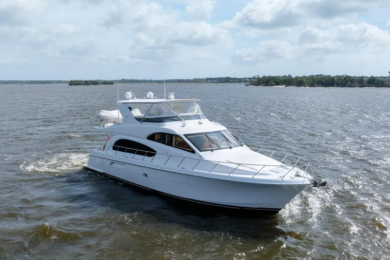 Slide: The Image of 2008 Hatteras 64 Motor Yacht cruising on open water under a cloudy sky. - 12