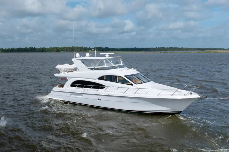 Slide: The Image of 2008 Hatteras 64 Motor Yacht cruising on open water under a cloudy sky. - 16