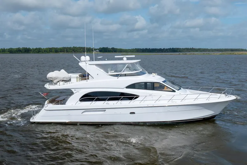 Slide: The Image of 2008 Hatteras 64 Motor Yacht cruising on a calm river under a cloudy sky. - 17