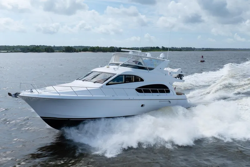 Slide: The Image of 2008 Hatteras 64 Motor Yacht cruising on open water under a cloudy sky. - 21