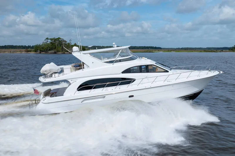 Slide: The Image of 2008 Hatteras 64 Motor Yacht cruising on open water under a cloudy sky. - 25