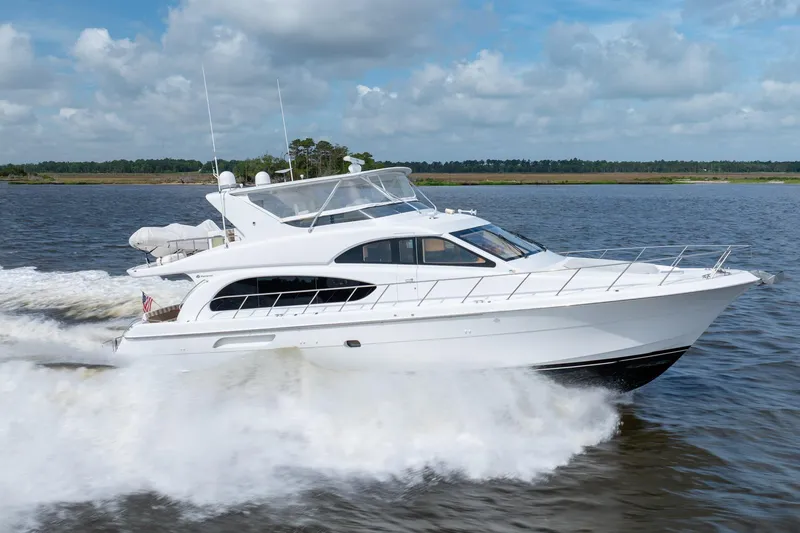 Slide: The Image of 2008 Hatteras 64 Motor Yacht cruising on open water under a cloudy sky. - 26