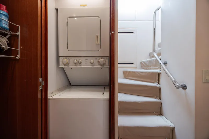 Slide: The Image of Laundry area with stacked washer-dryer beside stairs on 2008 Hatteras 64 Motor Yacht. - 50