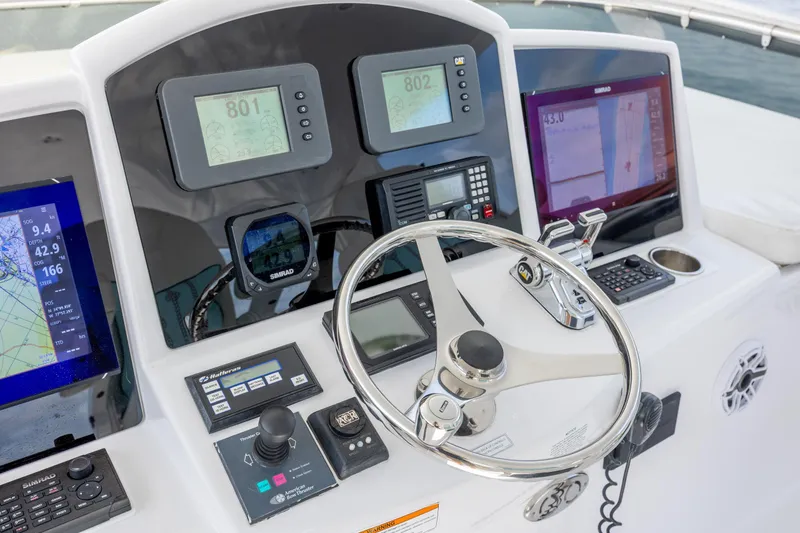 Slide: The Image of Control panel of a 2008 Hatteras 64 Motor Yacht with navigation instruments and steering wheel. - 83