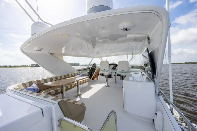 Slide: The Image of 2008 Hatteras 64 Motor Yacht deck with seating, table, and helm, cruising on open water. - 86