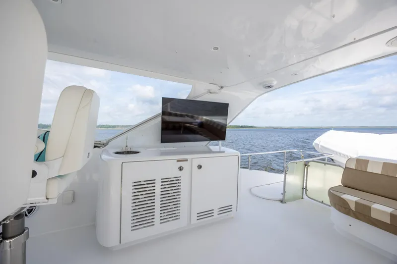 Slide: The Image of Luxurious 2008 Hatteras 64 Motor Yacht deck with seating and TV, overlooking serene waters. - 92