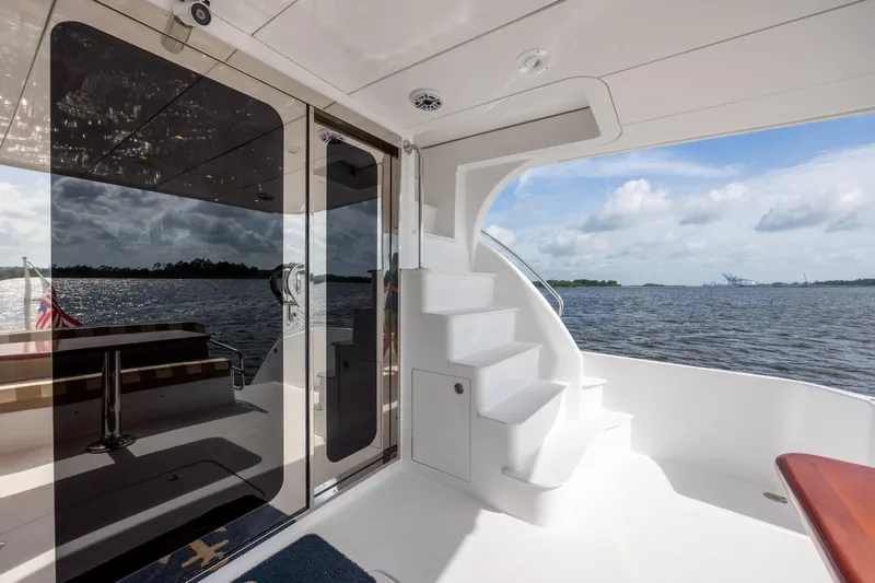 Slide: The Image of 2008 Hatteras 64 Motor Yacht deck with stairs, overlooking serene waters. - 96