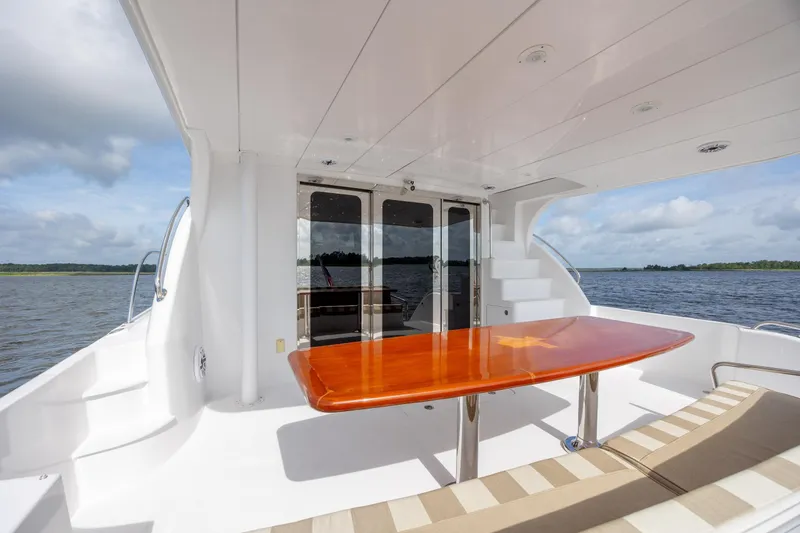 Slide: The Image of 2008 Hatteras 64 Motor Yacht aft deck with polished table and scenic water view. - 97