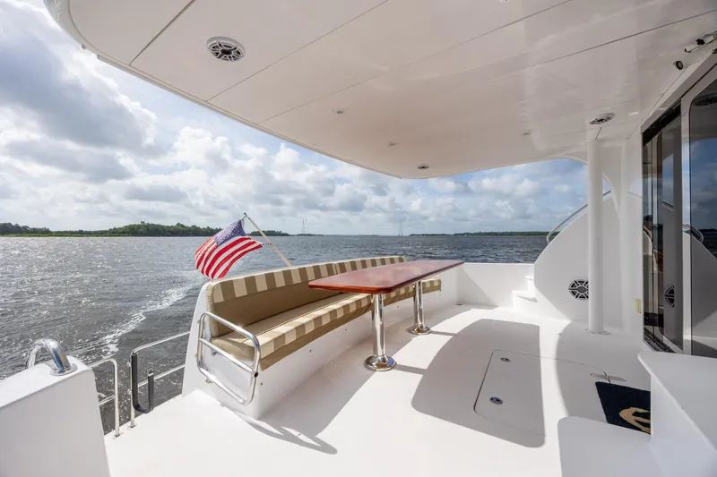 Slide: The Image of 2008 Hatteras 64 Motor Yacht deck with seating, table, and American flag. - 98
