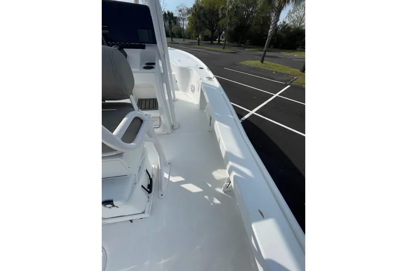 Slide: The Image of 2025 Sea Hunt BX 22 BR boat interior with seating and console, parked outdoors. - 13