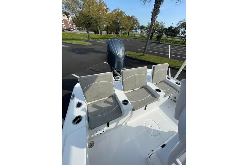 Slide: The Image of 2025 Sea Hunt BX 22 BR boat with cushioned seating and outboard motor in a parking area. - 8
