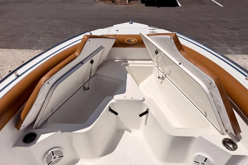 Slide: The Image of 2010 Sea Hunt Ultra 210 boat interior with open storage compartments and tan cushions. - 11