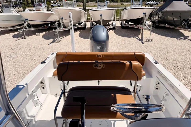Slide: The Image of 2010 Sea Hunt Ultra 210 boat interior with Yamaha 150 engine, parked among other boats. - 15