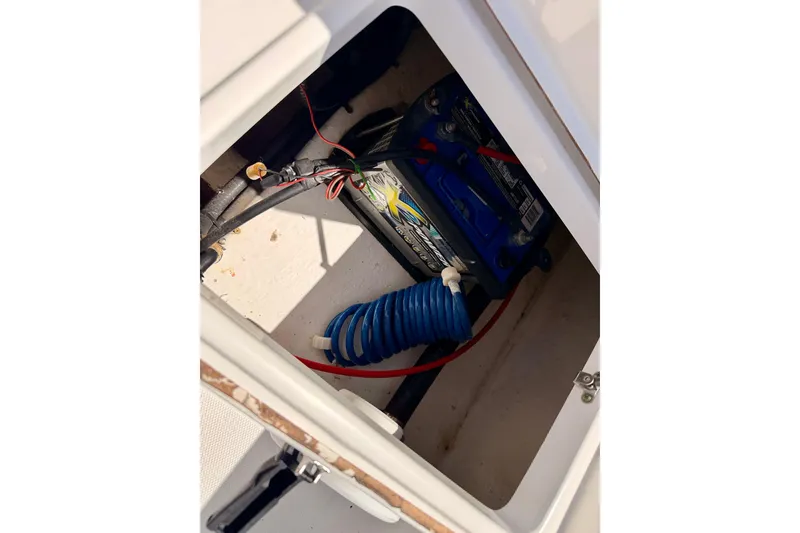Slide: The Image of Battery compartment of a 2010 Sea Hunt Ultra 210 boat with coiled blue hose. - 24