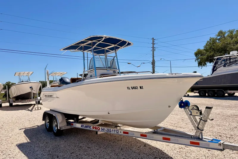 Slide: The Image of 2010 Sea Hunt Ultra 210 boat on trailer, parked outdoors under clear blue sky. - 3