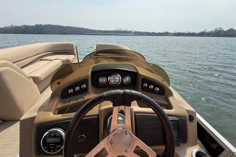 Slide: The Image of 2018 Bennington 23GSRFB boat dashboard with steering wheel on a calm lake. - 12