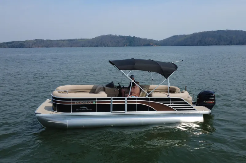 Slide: The Image of 2018 Bennington 23GSRFB pontoon boat cruising on a lake with scenic background. - 7
