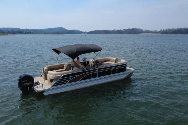 Slide: The Image of 2018 Bennington 23GSRFB pontoon boat cruising on a serene lake with scenic background. - 8