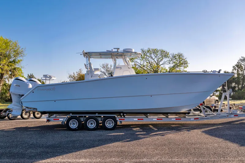 Slide: The Image of 2011 Freeman 33 boat on trailer with dual Yamaha engines, parked outdoors. - 9