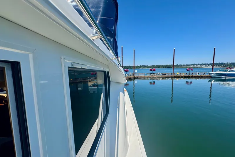 Slide: The Image of Side view of a 2000 Navigator 6300 Classic Pilothouse yacht docked by a serene lake. - 38