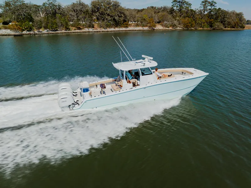 Slide: The Image of 2025 Freeman 38 boat cruising on a serene lake with lush trees in the background. - 5