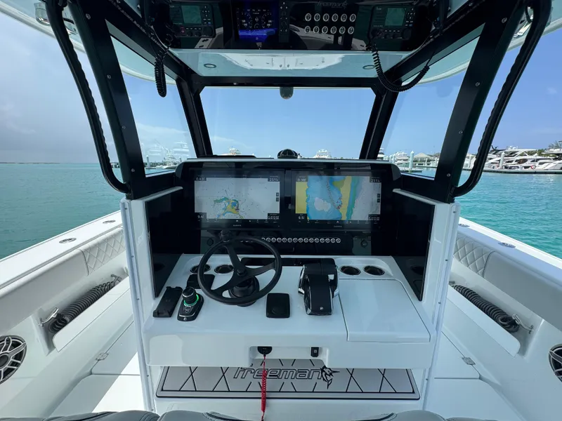 Slide: The Image of Helm of 2025 Freeman 38 boat with navigation screens and controls, docked in marina. - 11