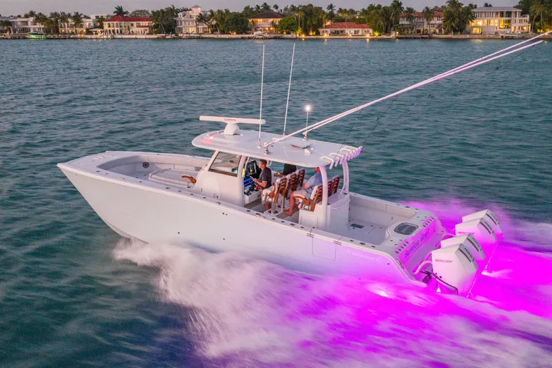 Slide: The Image of 2026 Freeman 38 boat cruising with vibrant purple underwater lights, near luxury waterfront homes. - 44