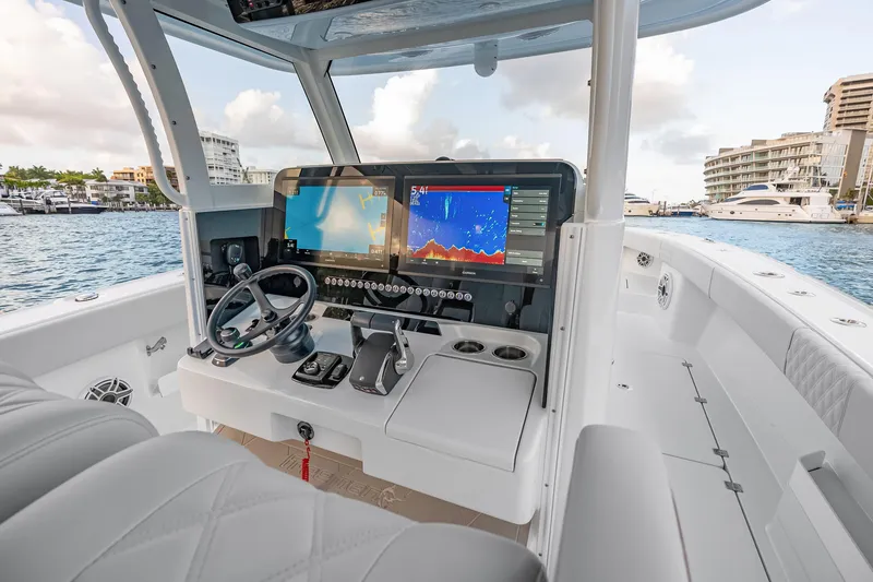 Slide: The Image of 2026 Freeman 38 boat cockpit with advanced navigation screens and steering wheel, docked in marina. - 47