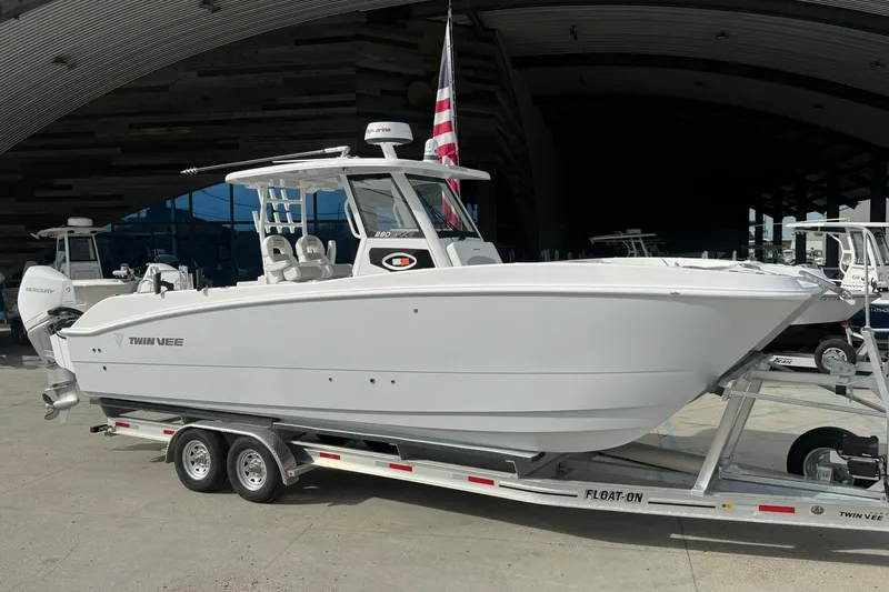 Slide: The Image of 2026 Twin Vee 280 GFX2 CC boat on trailer, displayed outdoors with American flag. - 15