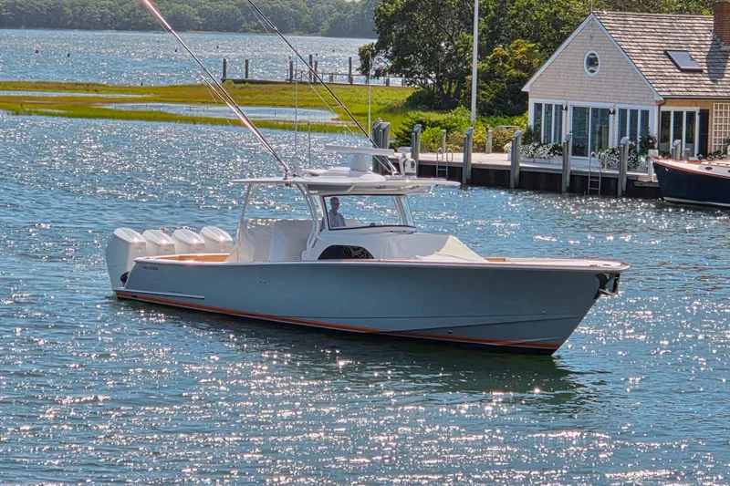 Slide: The Image of 2023 Valhalla Boatworks V-46 cruising on a sunny waterfront near a dockside house. - 11