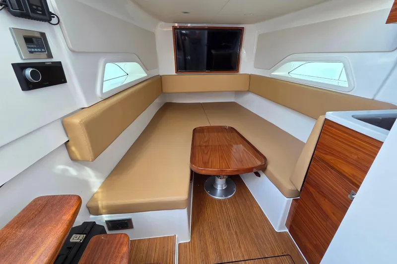 Slide: The Image of 2023 Valhalla Boatworks V-46 interior with beige seating, wooden table, and modern amenities. - 39
