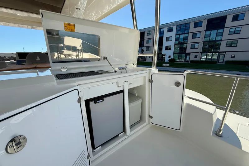 Slide: The Image of Outdoor kitchenette on 2023 Beneteau Swift Trawler 48, featuring grill and mini fridge. - 14
