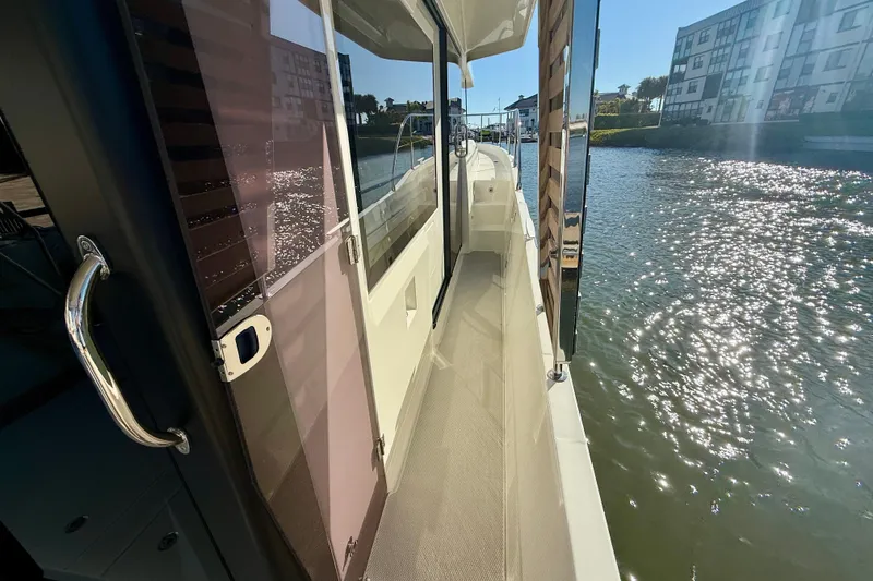 Slide: The Image of 2023 Beneteau Swift Trawler 48 side deck with waterfront view. - 23