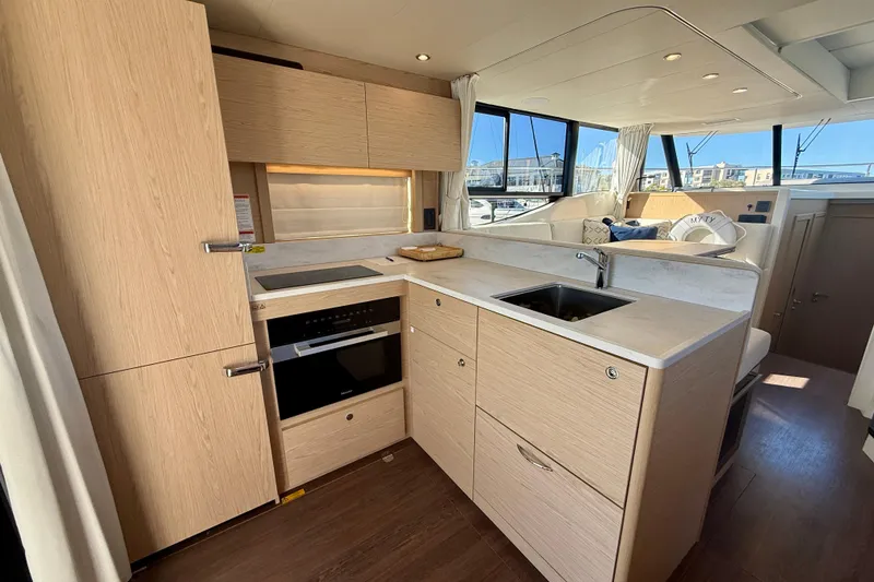 Slide: The Image of Modern kitchen interior on 2023 Beneteau Swift Trawler 48 yacht, featuring sleek cabinetry and appliances. - 24