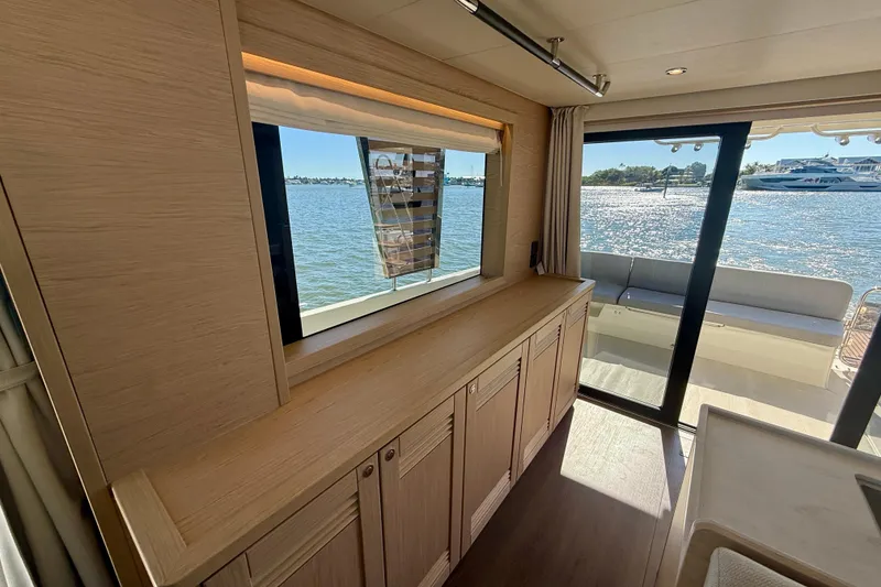 Slide: The Image of Interior view of 2023 Beneteau Swift Trawler 48, featuring elegant wood cabinetry and waterfront scenery. - 25