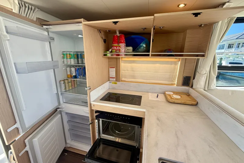 Slide: The Image of Modern kitchen in 2023 Beneteau Swift Trawler 48 with fridge, stove, and storage. - 26