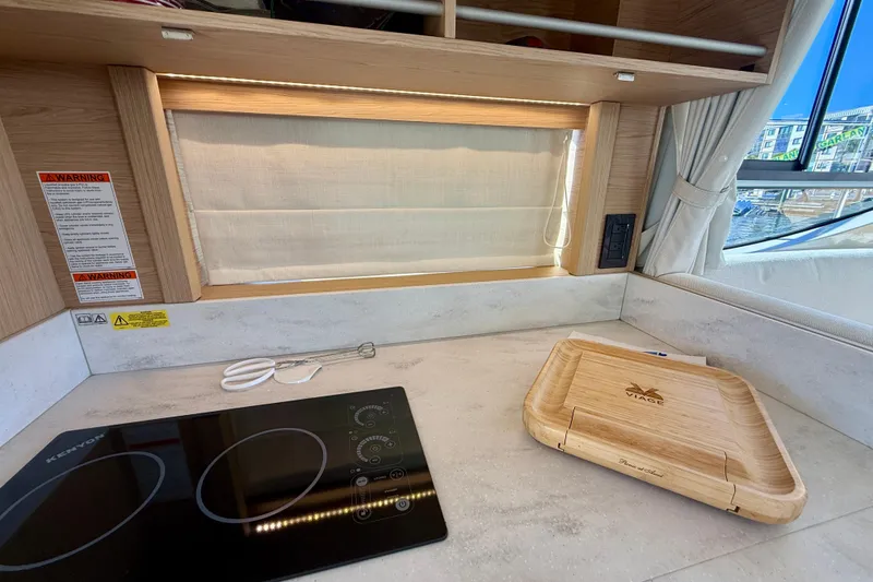 Slide: The Image of Modern kitchen area in 2023 Beneteau Swift Trawler 48 with induction cooktop and wooden tray. - 27