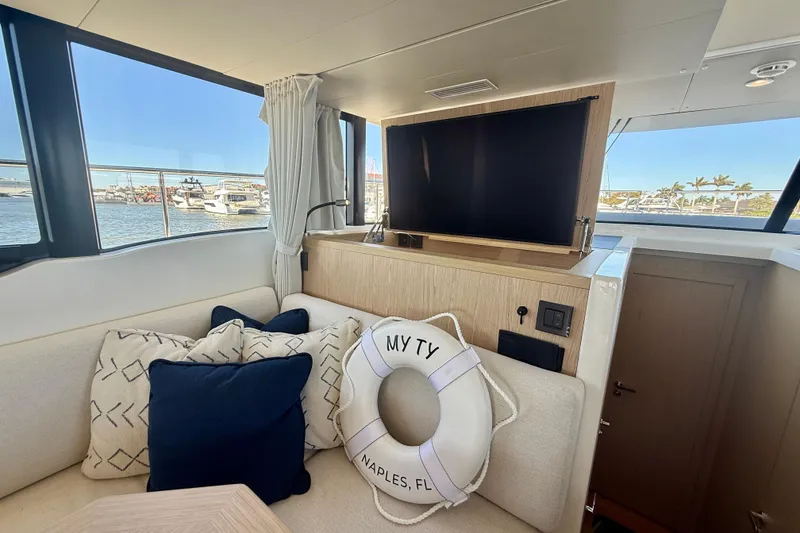 Slide: The Image of Interior of 2023 Beneteau Swift Trawler 48 with TV, cushions, and life preserver. - 30