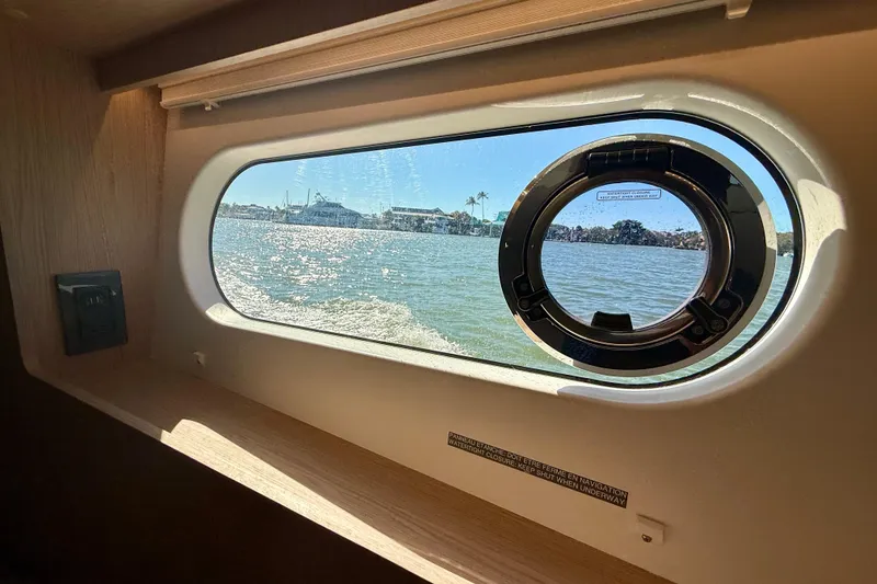 Slide: The Image of Porthole view from 2023 Beneteau Swift Trawler 48, showcasing serene waters and distant shoreline. - 37