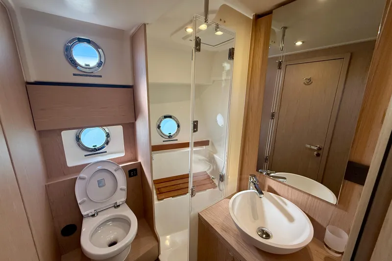 Slide: The Image of 2023 Beneteau Swift Trawler 48 bathroom with modern fixtures and porthole windows. - 38